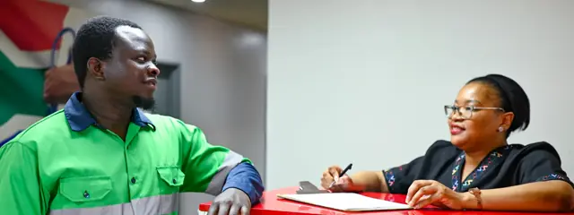 A Care Net receptionist taking a call at the front desk under the company sign